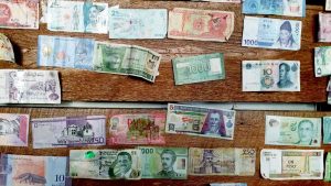 Bills of varying currencies laying on a wooden background.