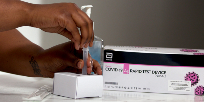 Person's hand extracting a rapid test from a kit.