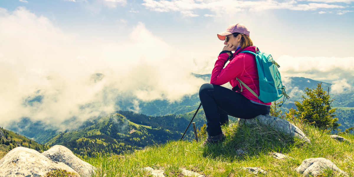 Woman sitting on mountain top reflecting