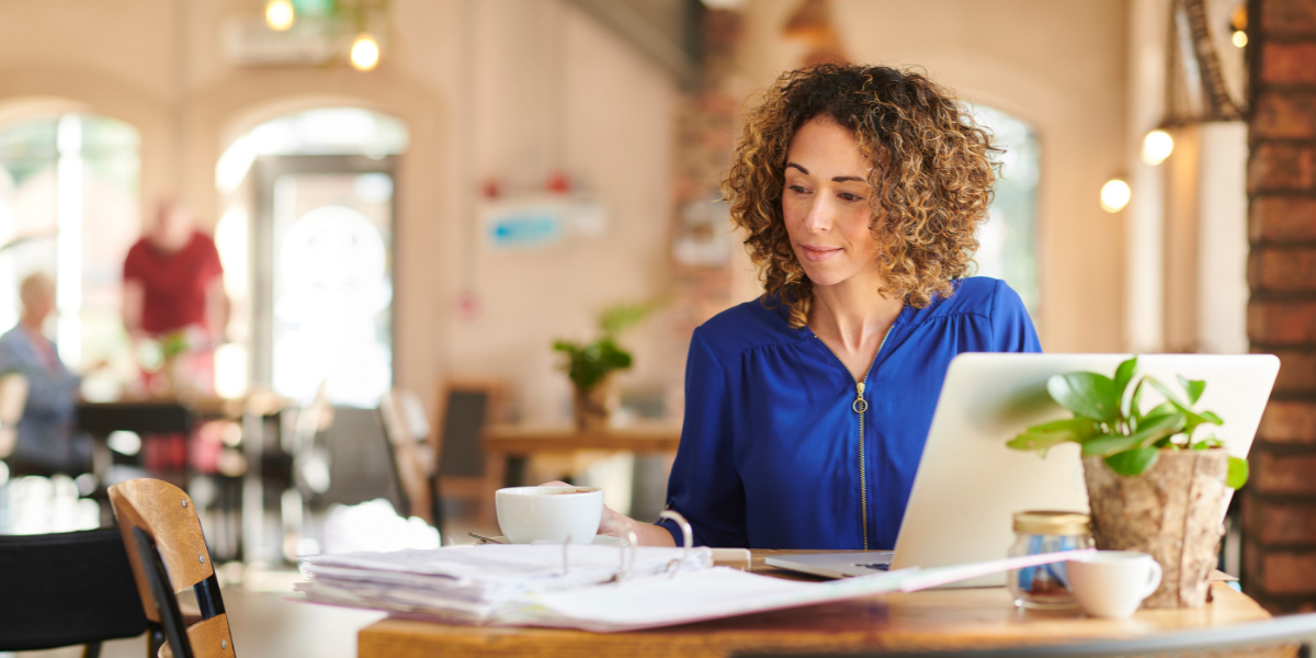 Member experience - middle-aged woman with curly hair in a blue shirt, remotely working.