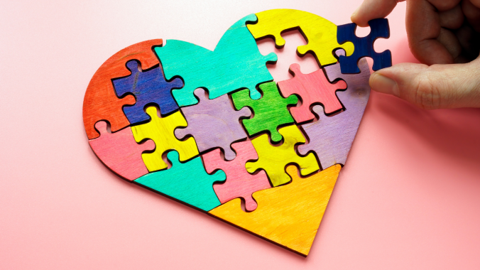 A heart puzzle with varying colours on a pink table.