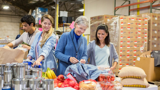 Four individuals are volunteering at a food bank.